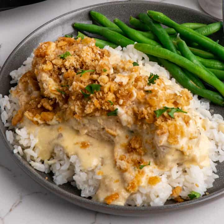 Close up of slow cooker ritz cracker chicken over rice on a grey plate with green beans.