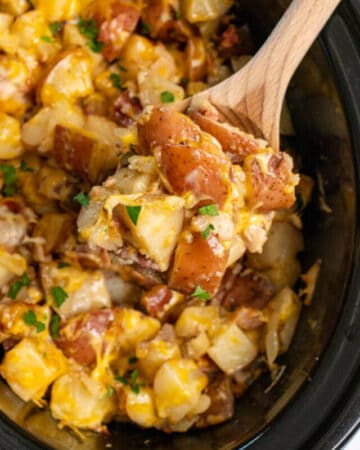 Close up of slow cooker cheesy ranch potatoes on a wooden spoon.
