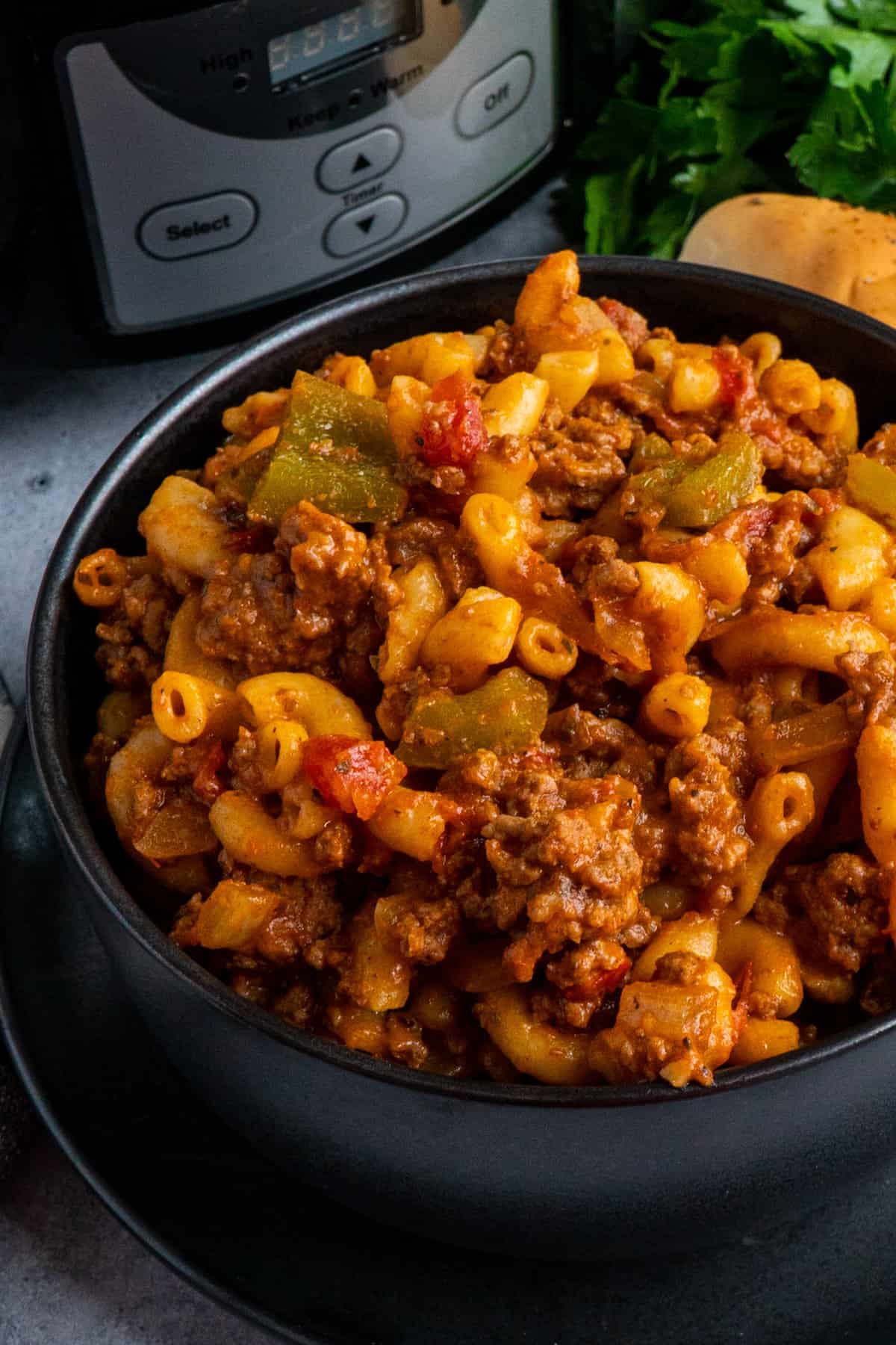 Crock Pot goulash in a black bowl and slow cooker in the background.