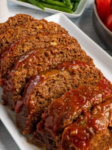 Close up of crock pot meatloaf with a glaze on a white plate.
