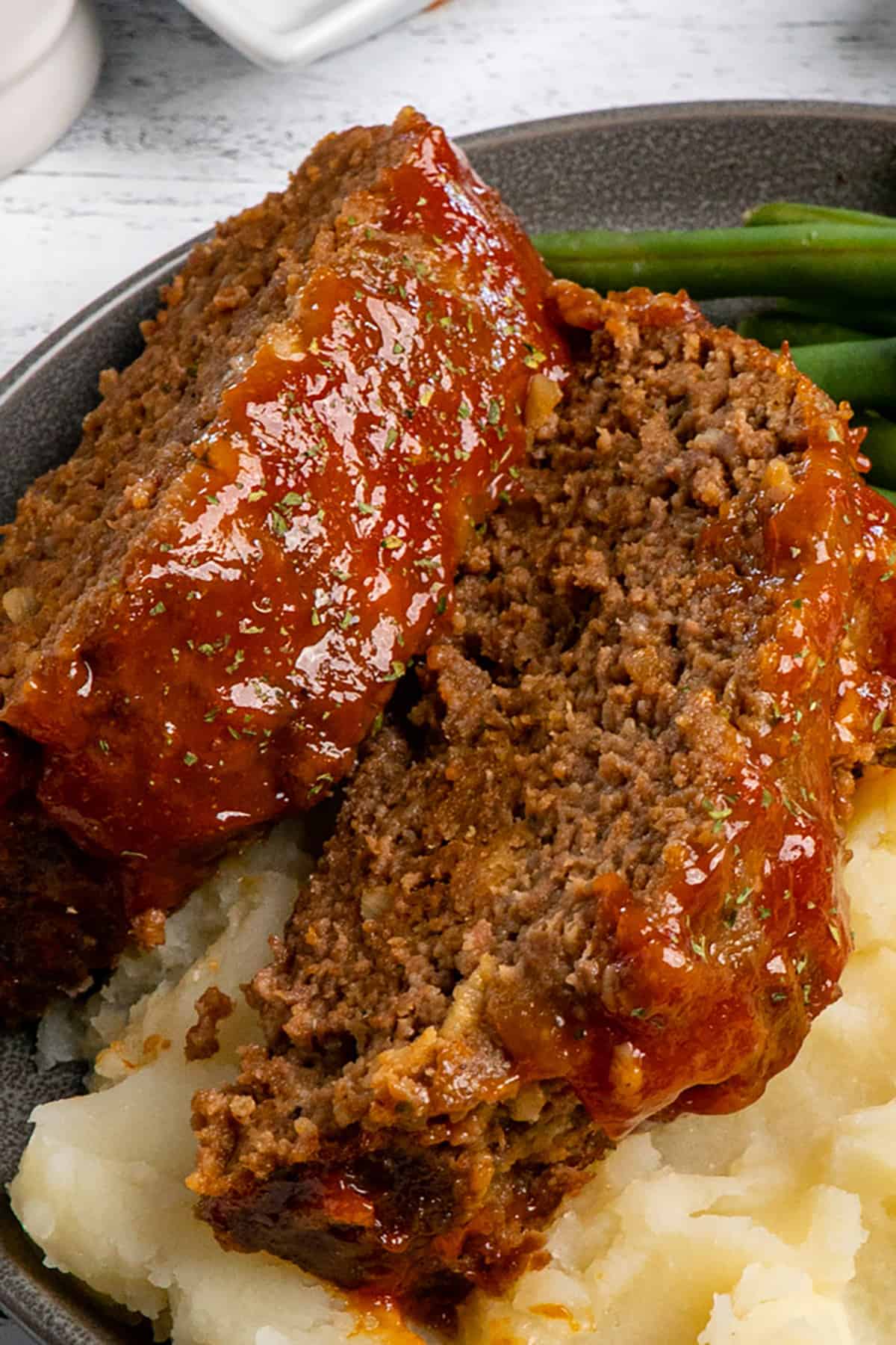 Close up of meatloaf on mashed potatoes.