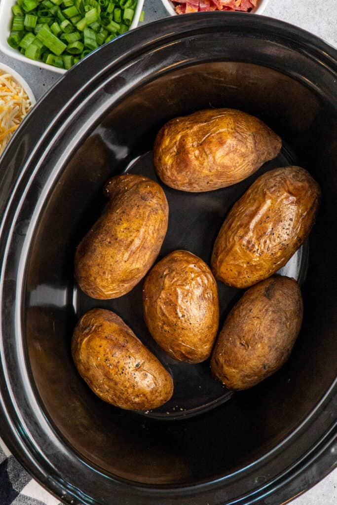 Overhead look at slow cooker baked potatoes with olive oil and pepper on them.