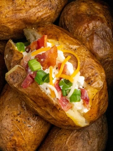 Crockpot baked potatoes with the one on top loaded up with toppings.