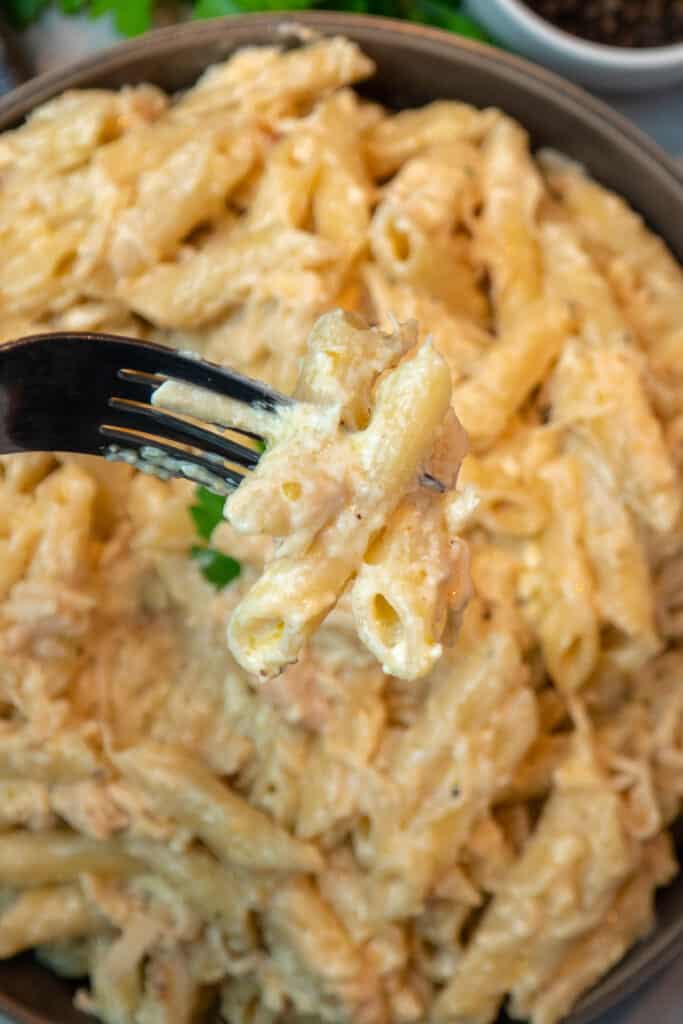Close up of Olive Garden chicken pasta on a fork over a slow cooker.