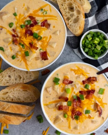 Two bowls of Crock-Potato baked potato soup garnished with bacon, cheese, and green onions.