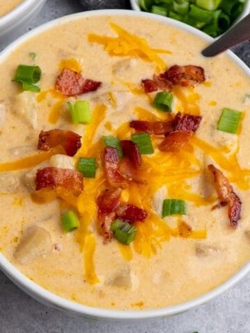 Crock-Pot potato soup in a white bowl with cheese and bacon on top.