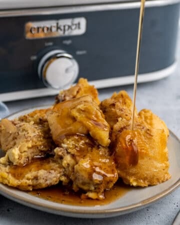 Crock-Pot French toast on a plate with maple syrup being poured on it.