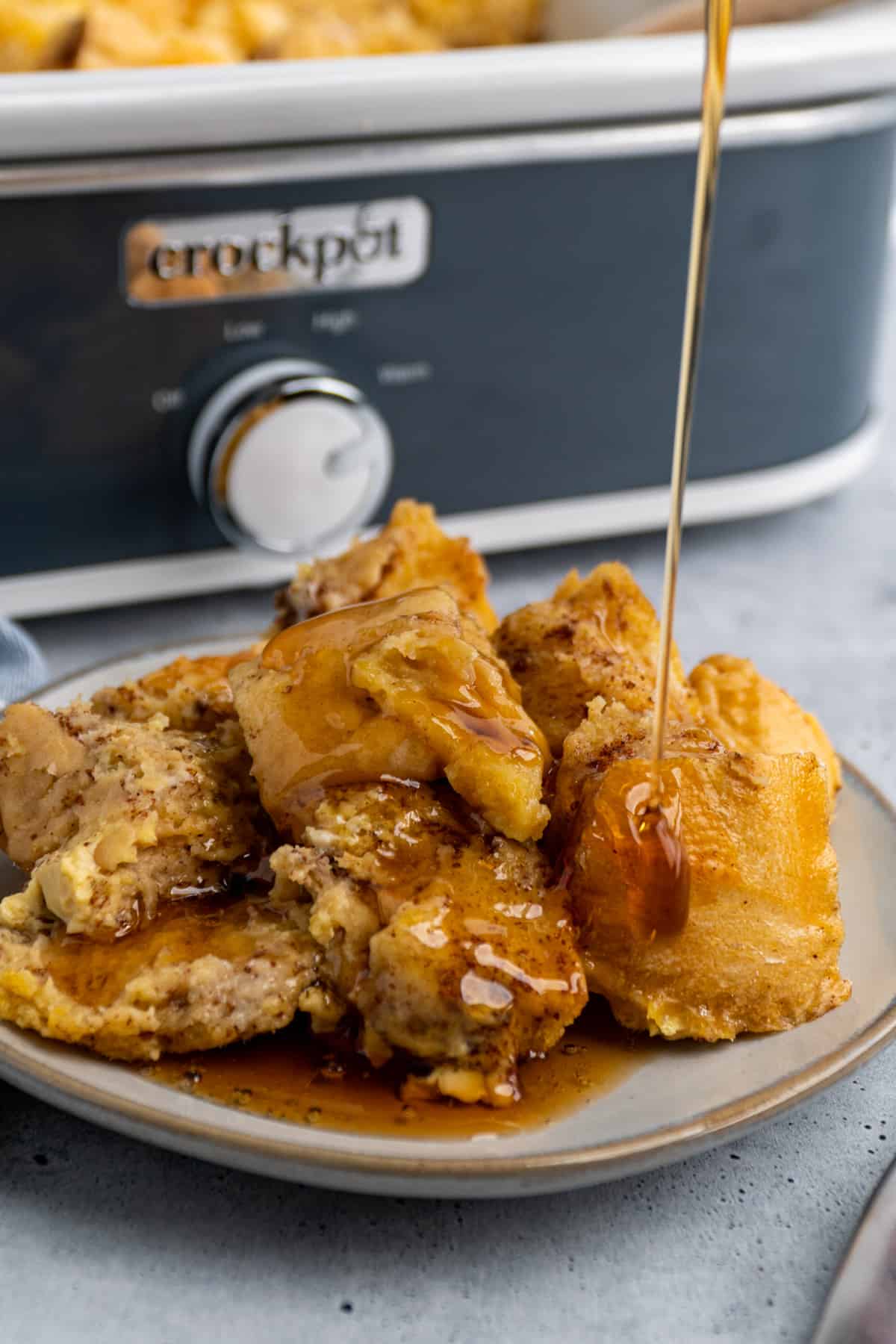 Crock Pot French toast on a plate with maple syrup being poured on it.