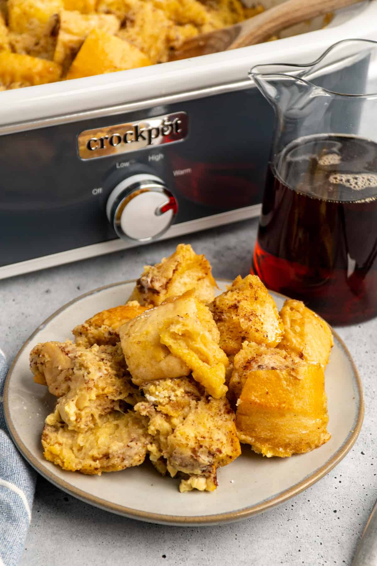 Crock Pot French toast on a plate with a slow cooker in the background.