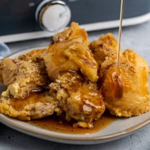 Crock Pot French toast on a plate with maple syrup being poured on it.