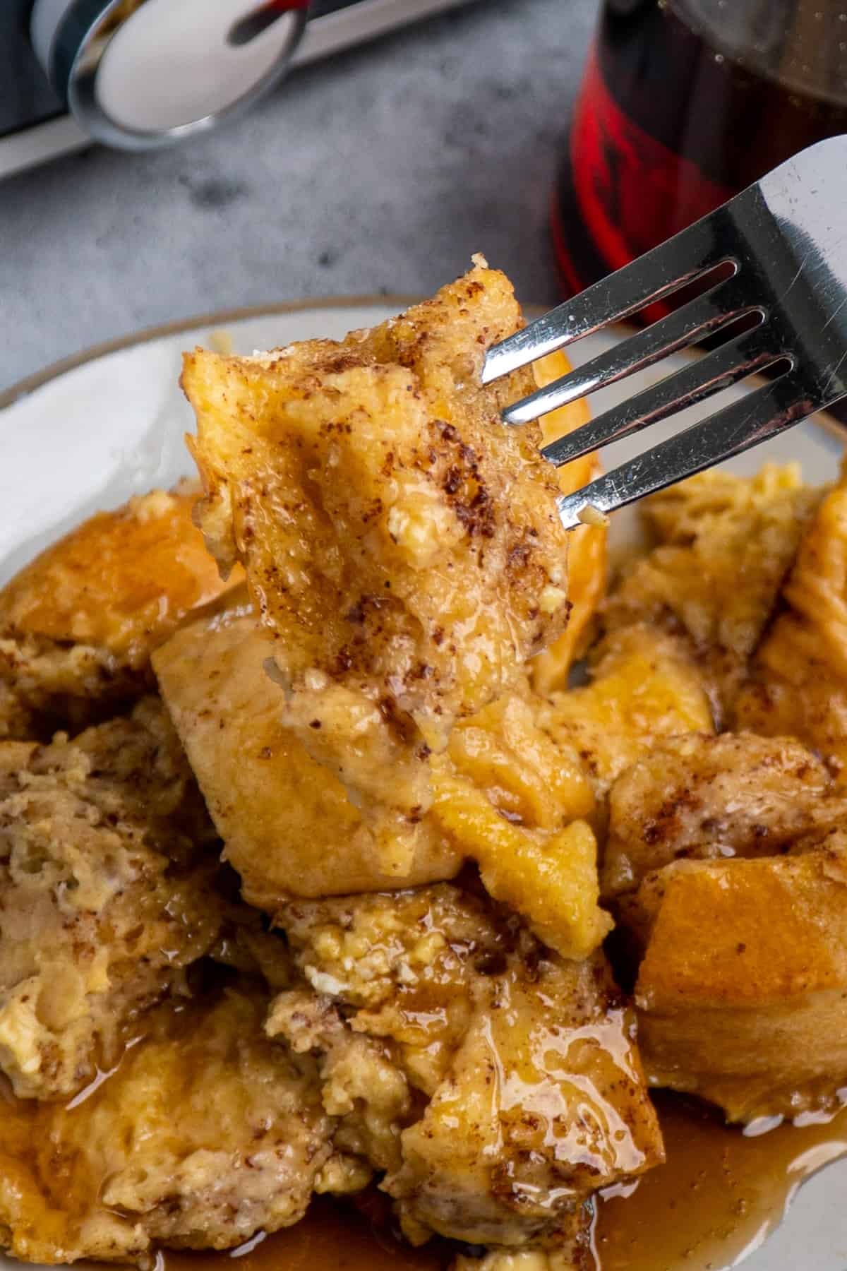 Close up of French toast on a fork over a plate of French toast.