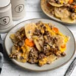 Crock Pot hamburger potato casserole on two plates in front of a slow cooker.