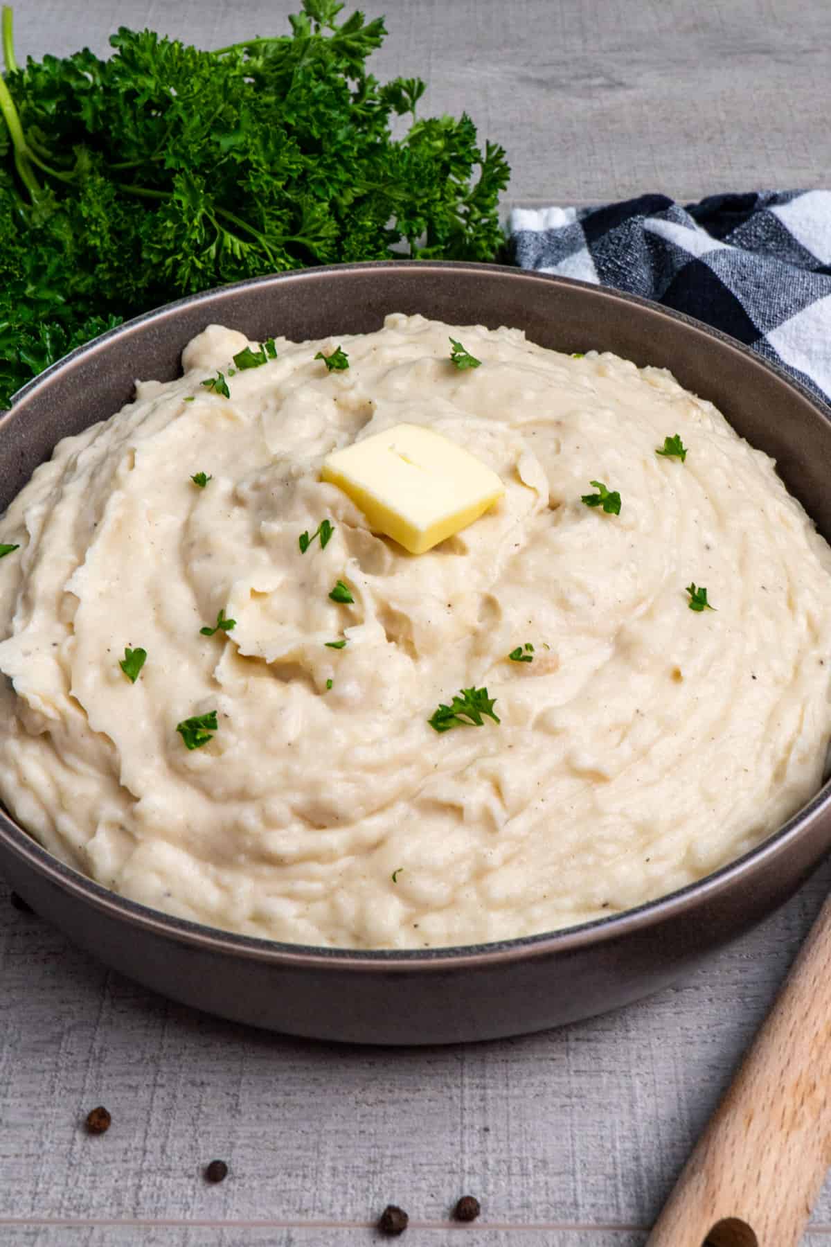 Close up of Crock-Pot mashed potatoes in a grey bowl garnished with butter.