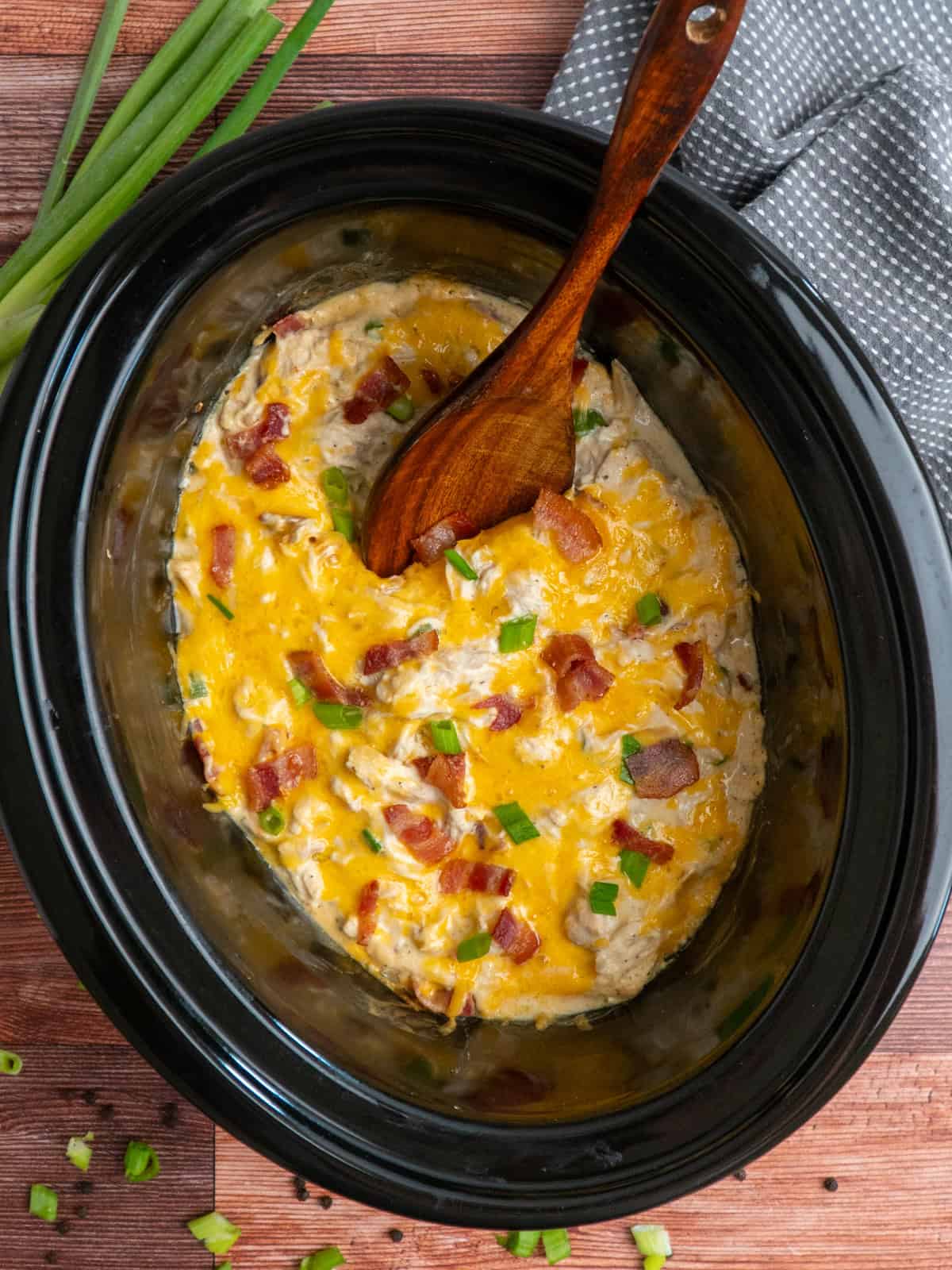 Crack chicken in a crock pot with a wooden spoon ready to be served.