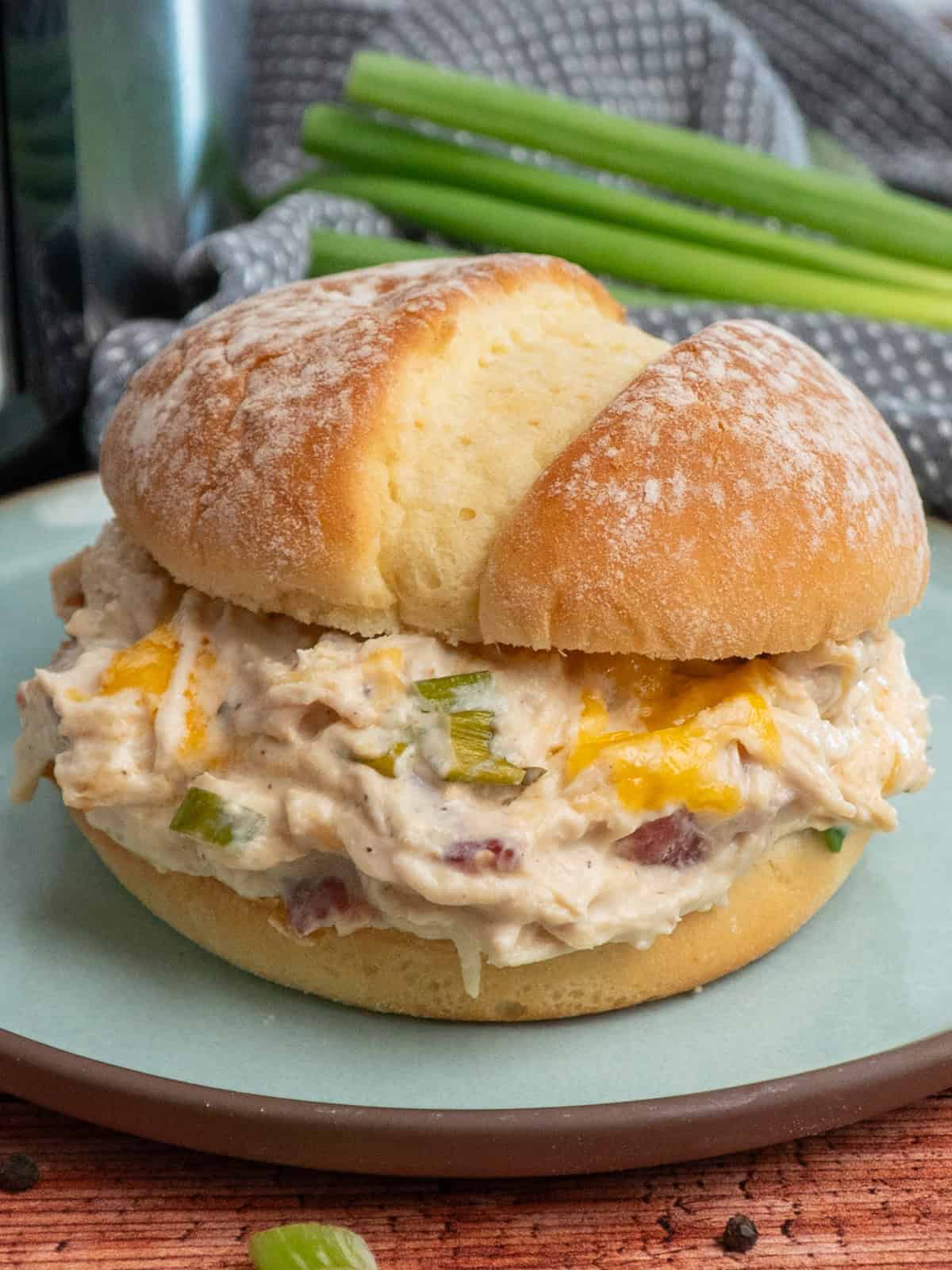 Crack chicken on a potato bun sitting on a plate and ready to eat.