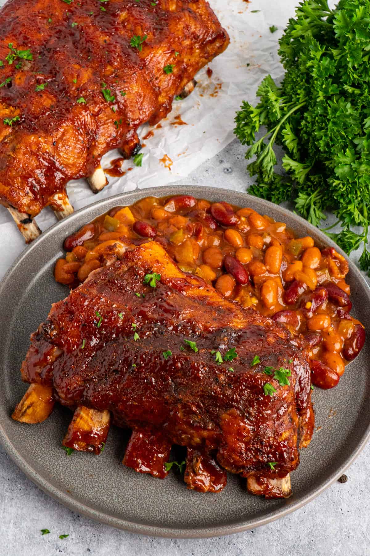 Country style ribs on a grey plate with baked beans
