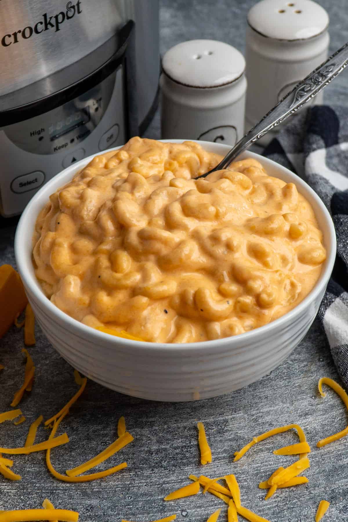 Close up of creamy crock pot mac and cheese in a white bowl with a fork in it.