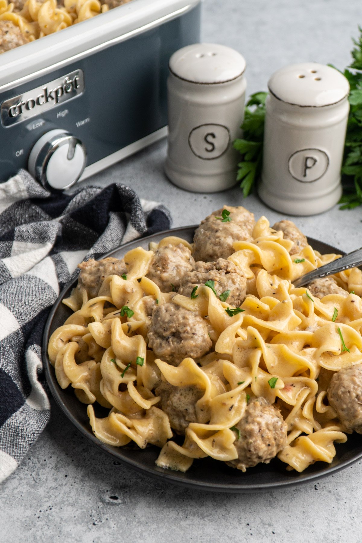 Crockpot Swedish meatballs on a black plate with salt and pepper in the background.