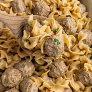 Close up of Swedish meatballs on a wooden spoon over a Crock-Pot.