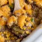 close of tater tot casserole on a wooden spoon over a crock pot.