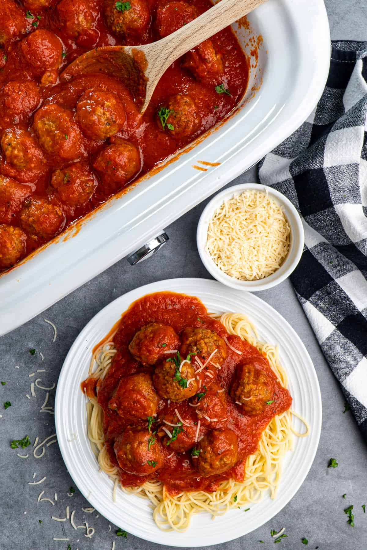 Overhead look at Crockpot meatballs over a plate of spaghetti and in a slow cooker.