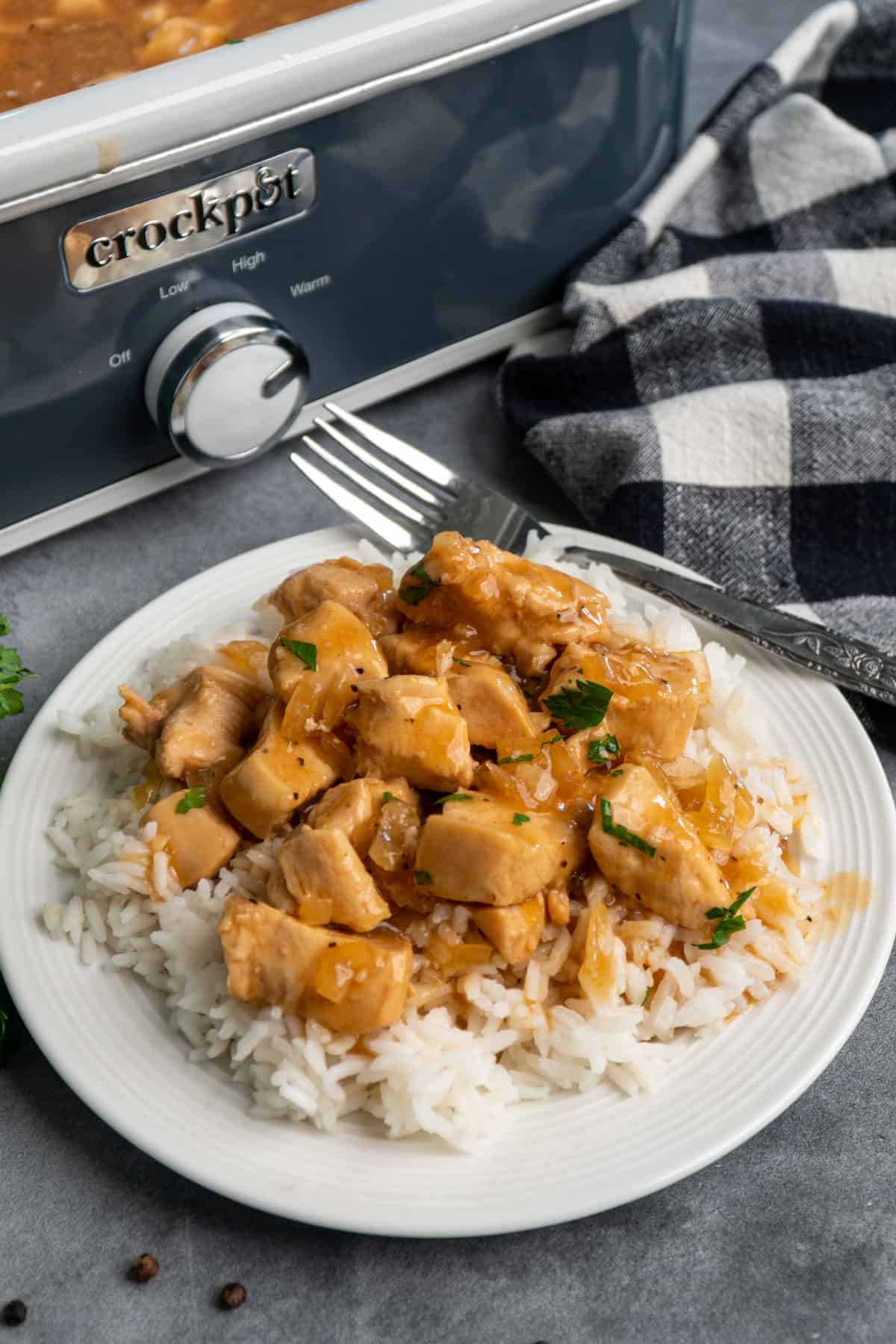 Close up of slow cooker honey bourbon chicken over rice on a white plate.