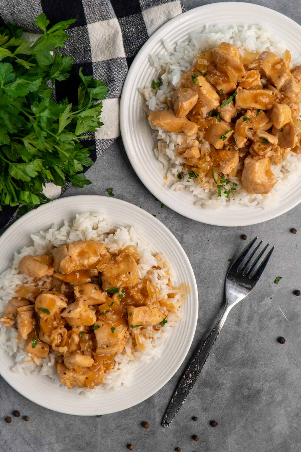 Two white plates with rice and honey bourbon chicken over the rice.