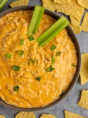 Overhead look at Crock Pot buffalo chicken dip in a grey bowl surrounded by tortilla chips.