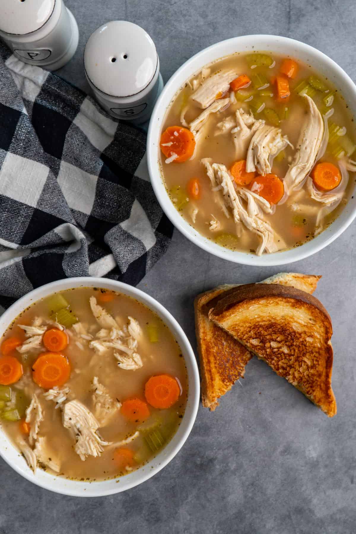 Overhead look a two white bowls of Crock Pot chicken and rice soup.