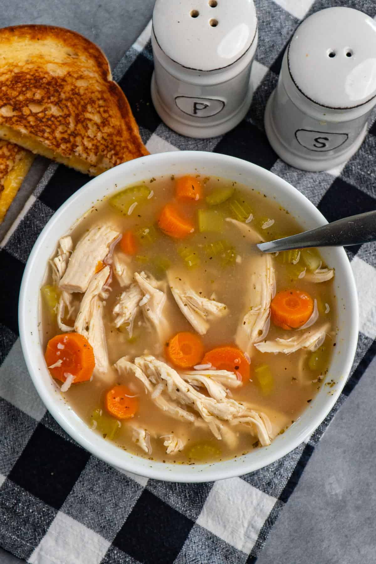 Close up of Crock Pot chicken and rice soup in a white bowl with a grilled cheese sandwich.