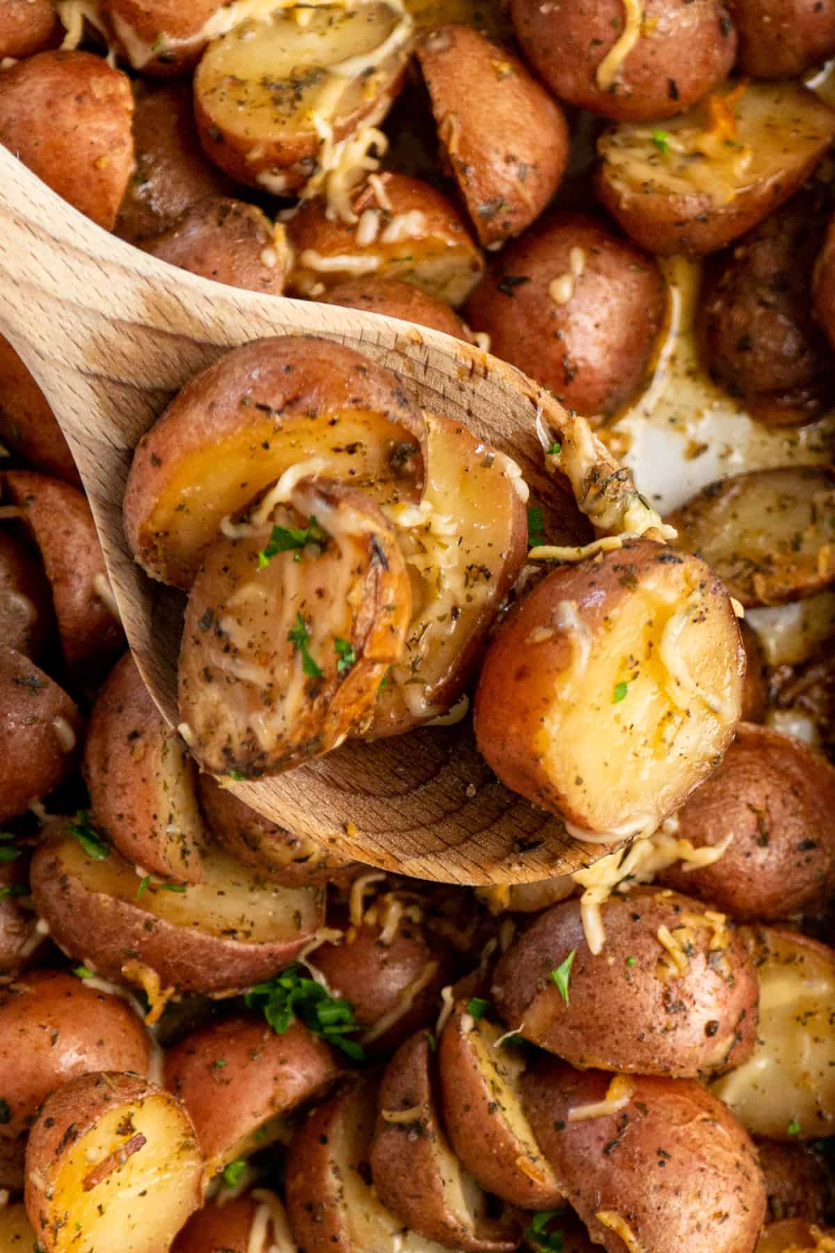 Close up of ranch potatoes on a wooden spoon over a slow cooker.