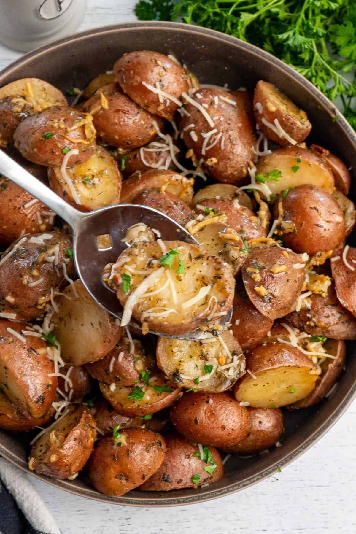 Ranch potatoes on a spoon over a bowl of more potatoes.