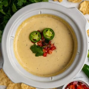 Close up of Crock-Pot white queso dip with fresh jalepenos and pico de gallo on top.