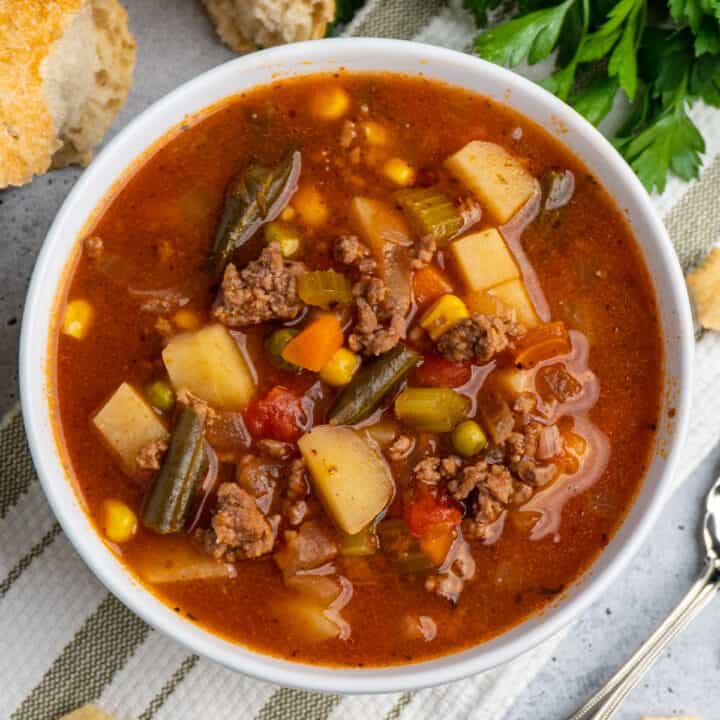 Overhead look a crockpot vegetable beef soup in a white bowl.