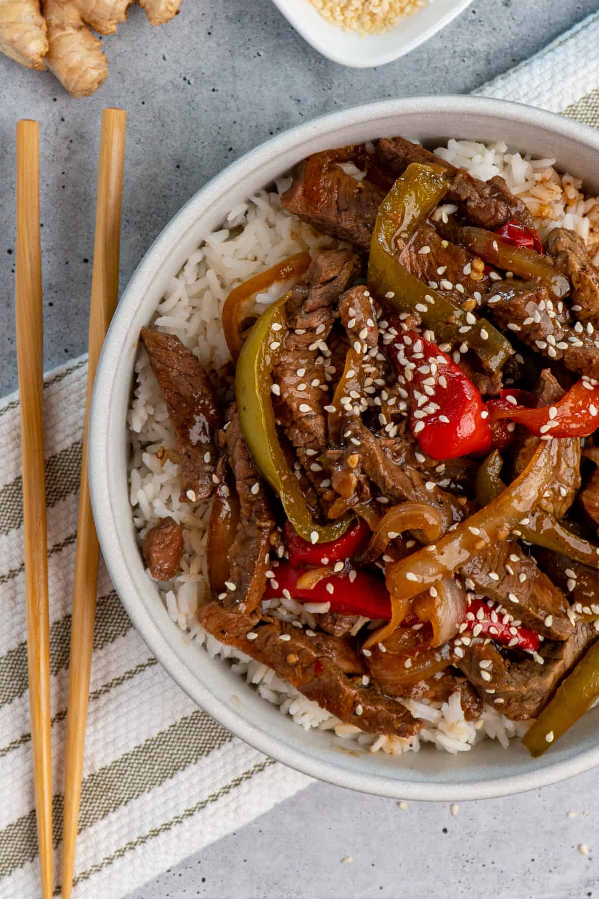 Image of crock pot pepper steak over white rice in a bowl.