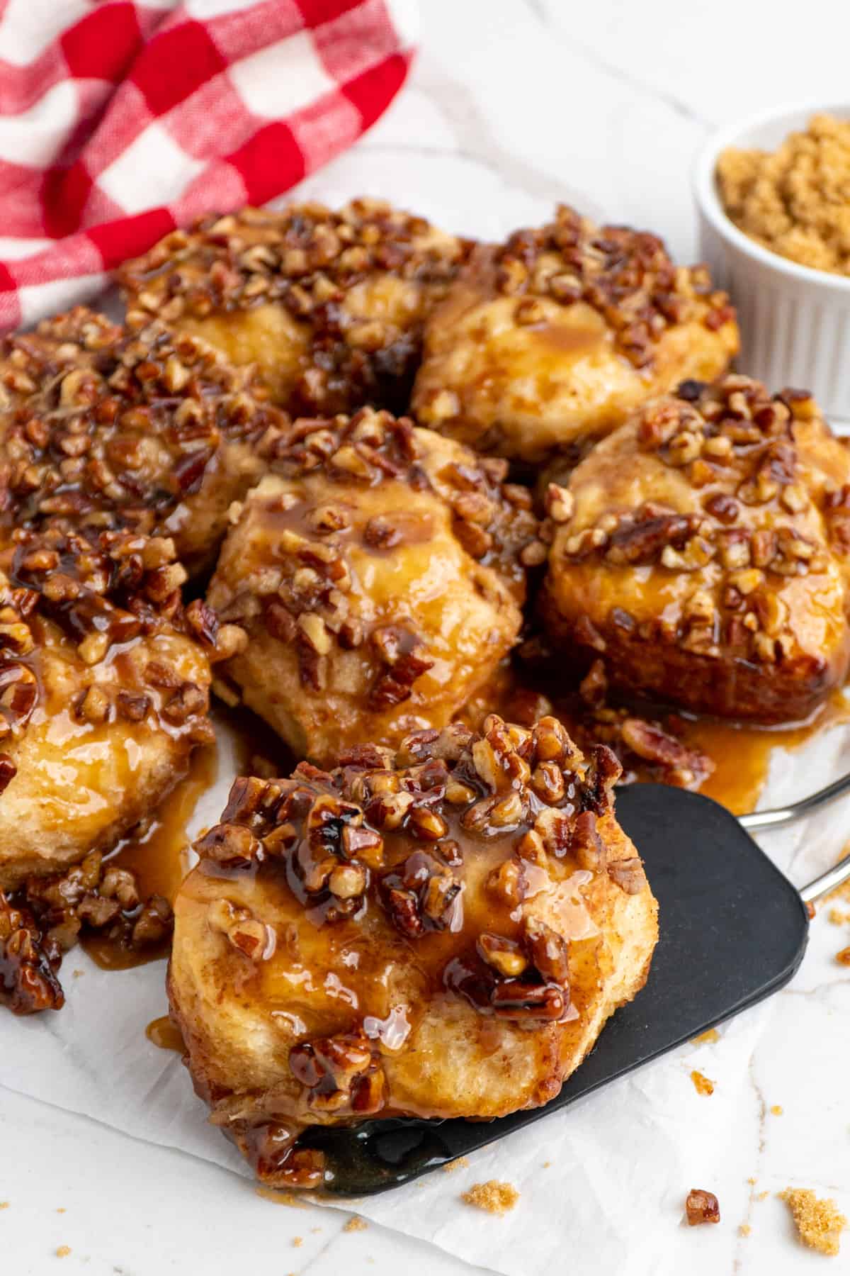 Overhead look at Crock Pot sticky buns on parchment paper with one sitting on a spatula.