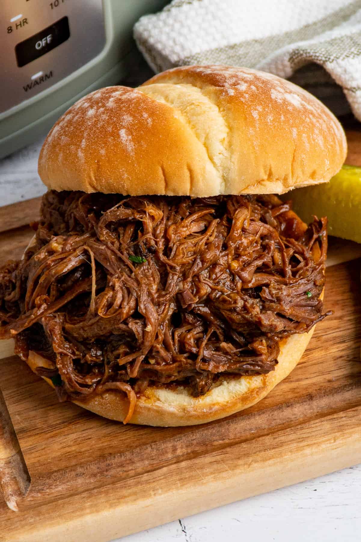 Close up of a slow cooker bbq beef sandwiches on a wood cutting board
