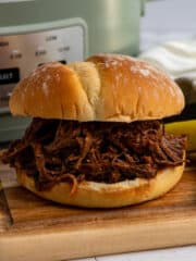 Close up of a slow cooker bbq beef sandwiches on a wood cutting board