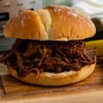 Close up of a slow cooker bbq beef sandwiches on a wood cutting board