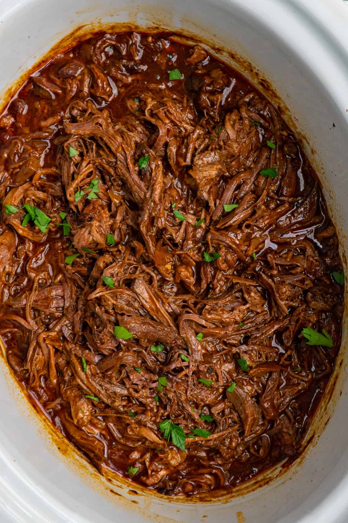 Overhead look at slow cooker BBQ beef in a crock pot.