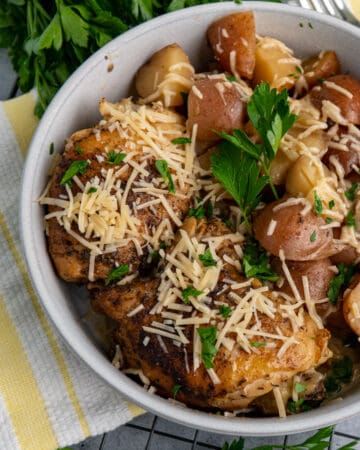 Close up of slow cooker garlic parmesan chicken in a bowl with potatoes.