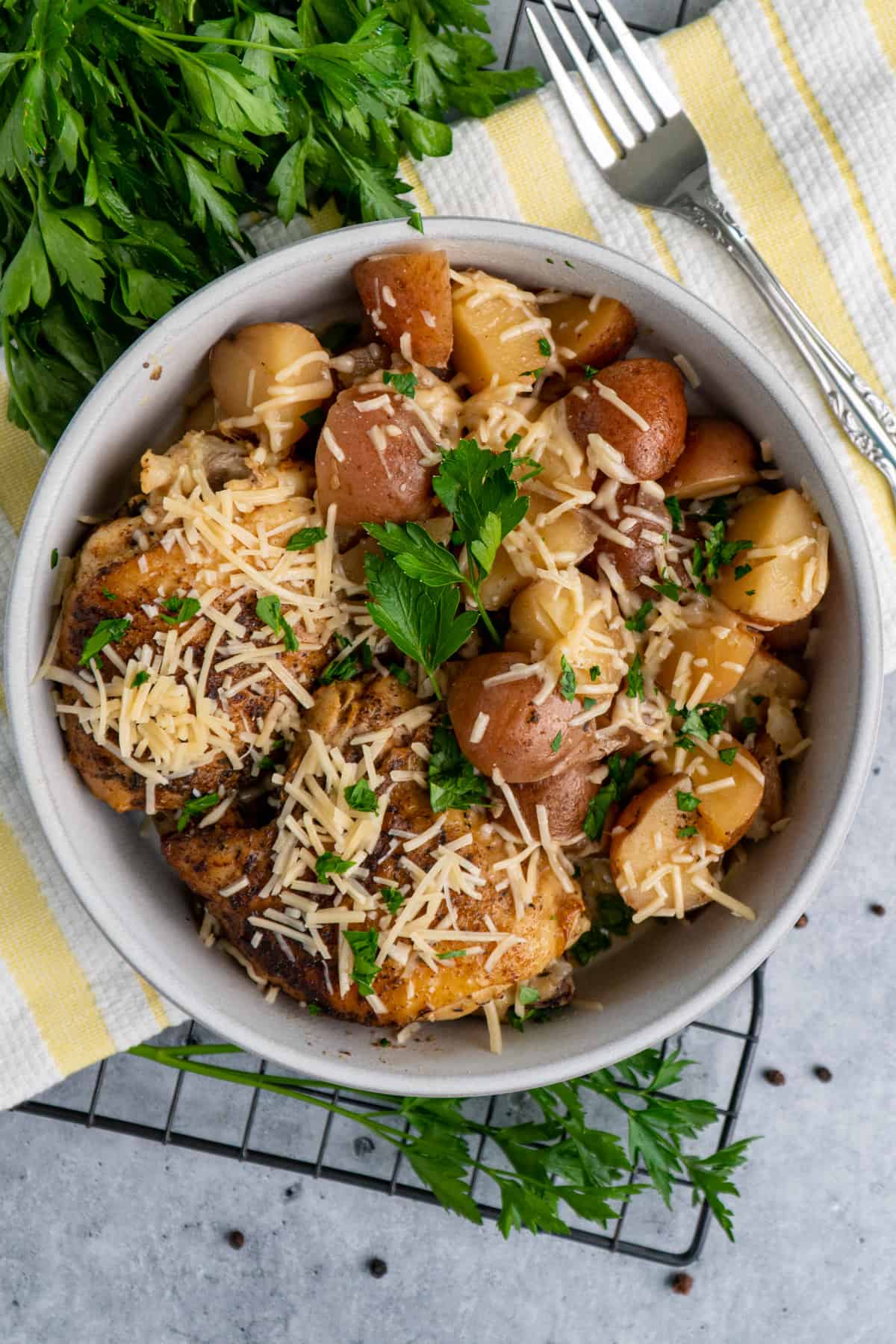 Close up of slow cooker garlic parmesan chicken in a bowl with potatoes.