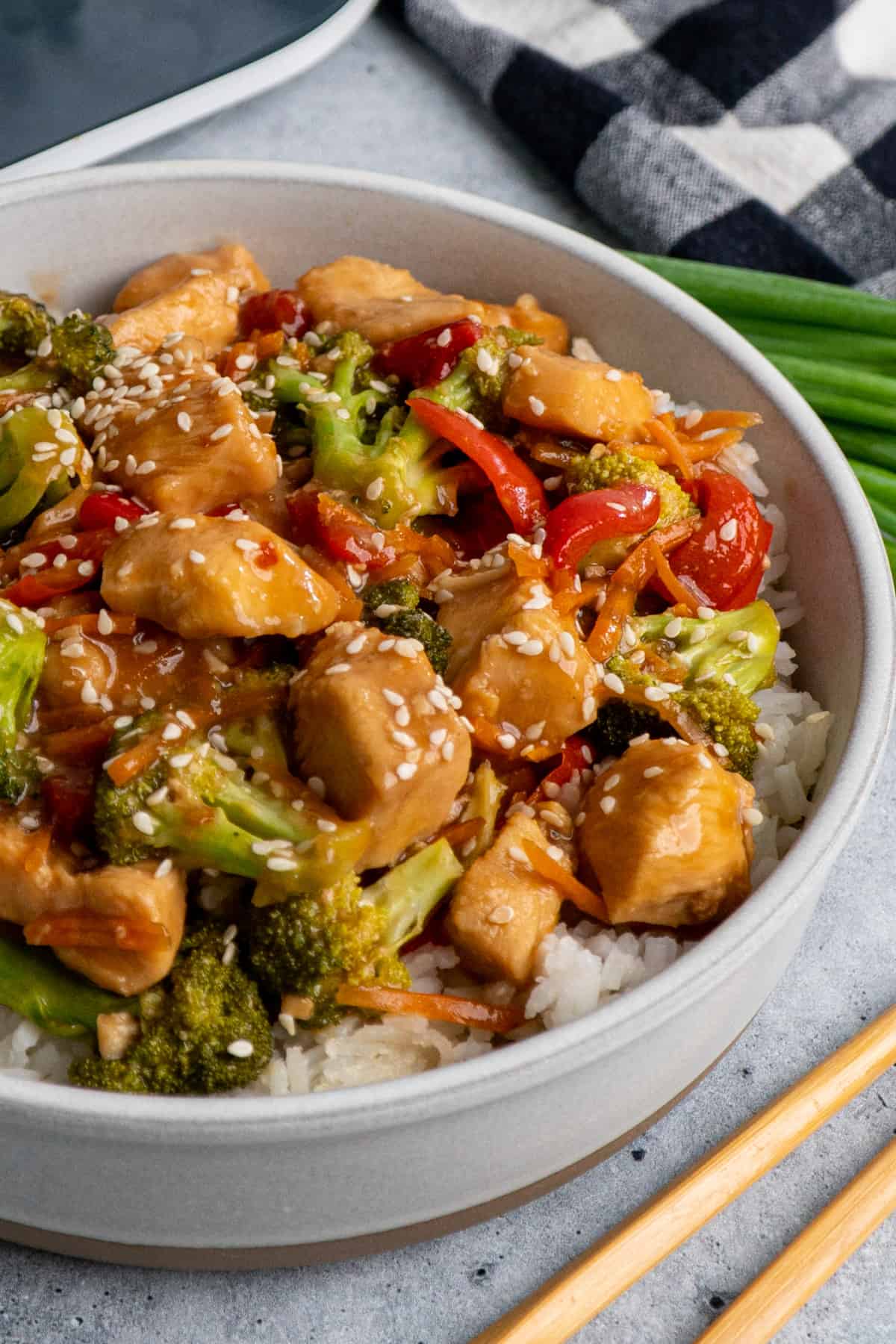 Close up of Mongolian chicken in a bowl over rice with sesame seeds on top.