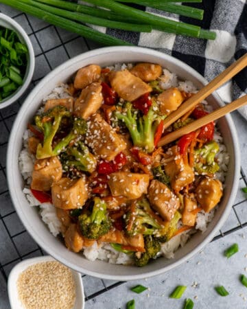 Overhead look at slow cooker mongolian chicken in a bowl over rice with chop sticks in it.