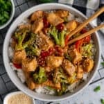 Overhead look at slow cooker mongolian chicken in a bowl over rice with chop sticks in it.