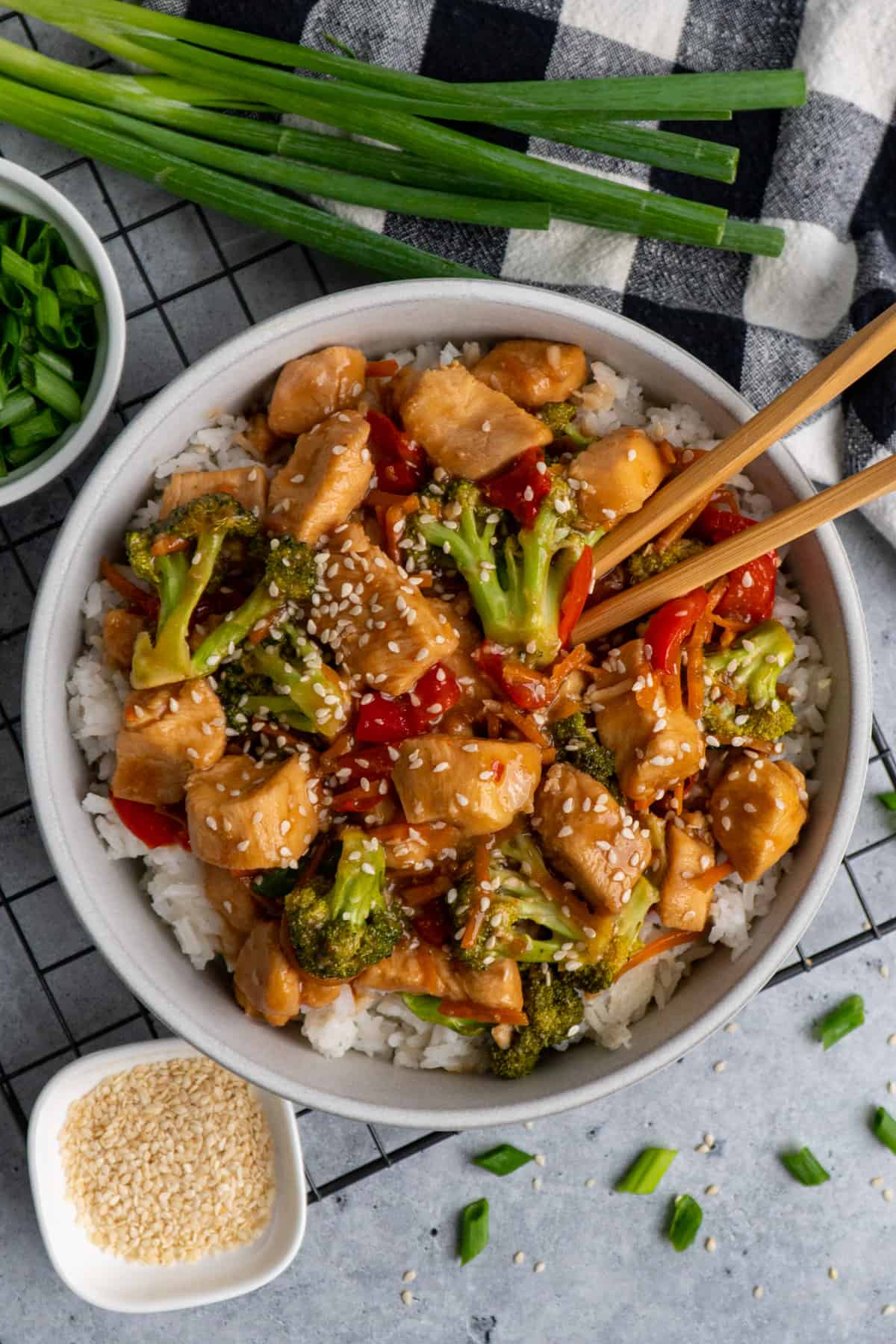 Overhead look at slow cooker mongolian chicken in a bowl over rice with chop sticks in it.