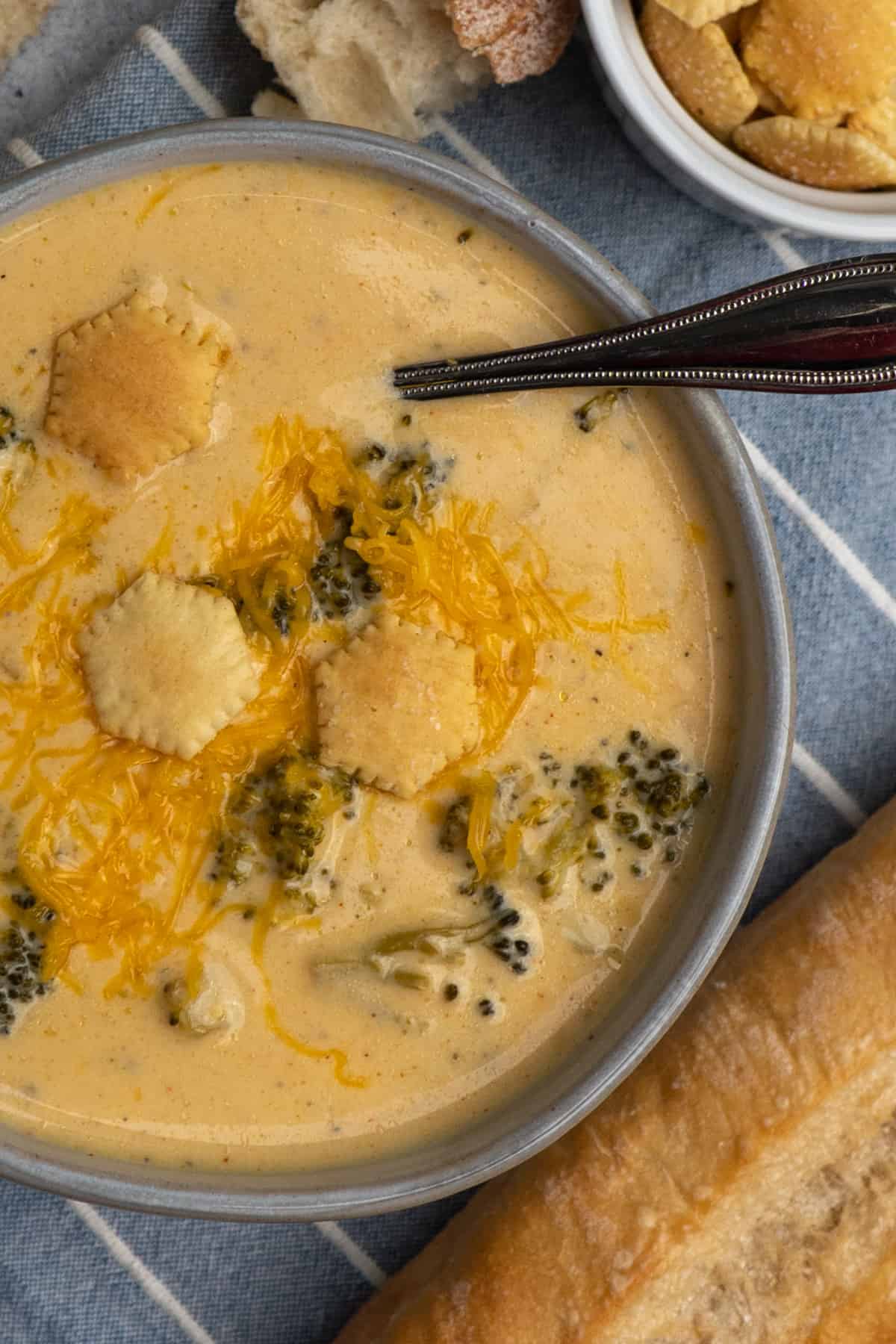 Overhead look at crock pot broccoli cheese soup in a gray bowl with cheese on top.