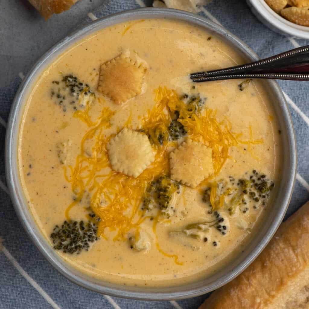 Overhead look at crock pot broccoli cheese soup in a gray bowl with cheese on top.