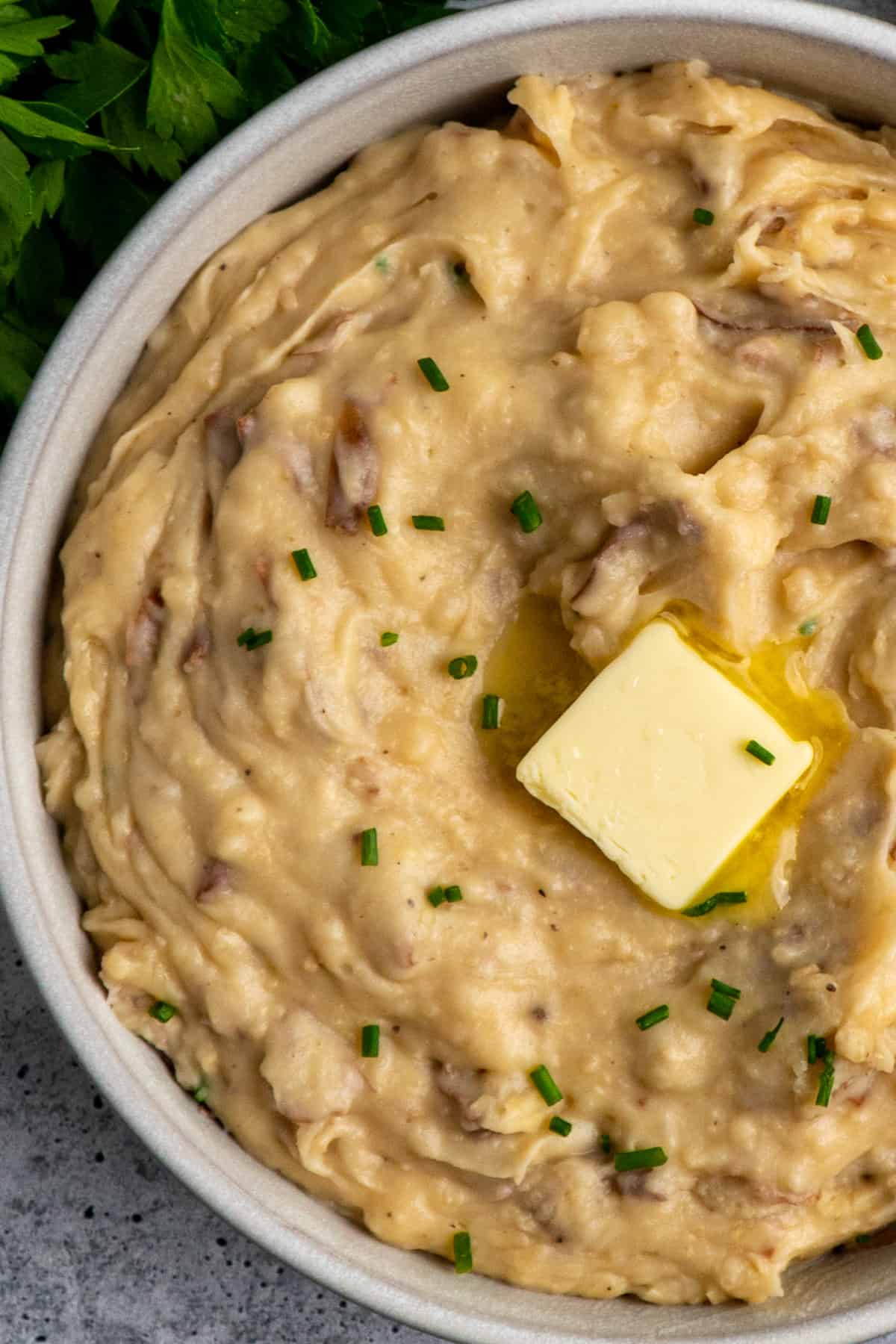 Creamy mashed potatoes in a bowl with chives and butter on top.