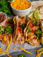 Image of three creamy crock pot salsa chicken tacos on a piece of parchment paper.